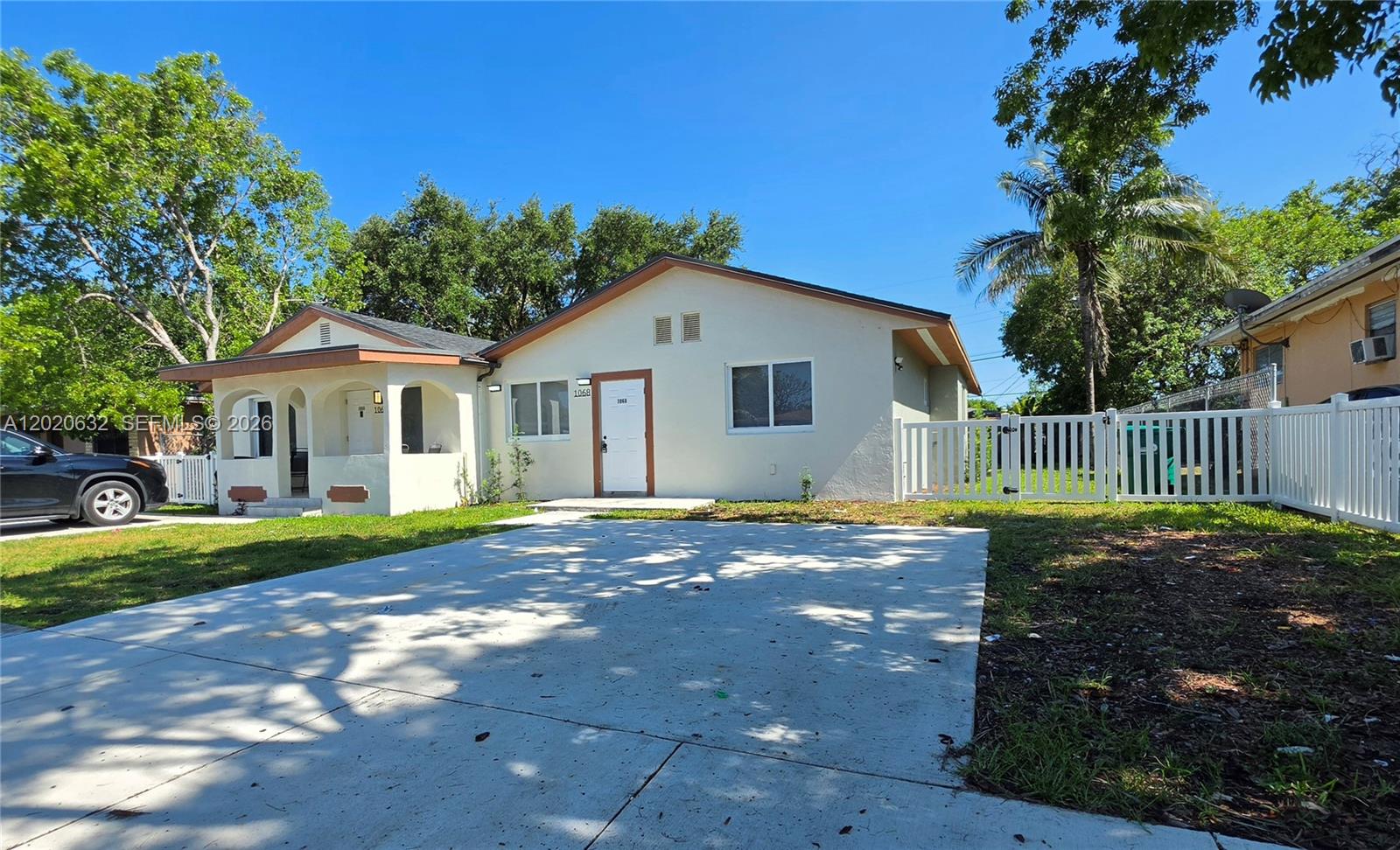 A single-story house with a white exterior, a concrete driveway, and a white picket fence — 1068 NW 112th St # 1068, Miami FL 33168, MIAMI, FL