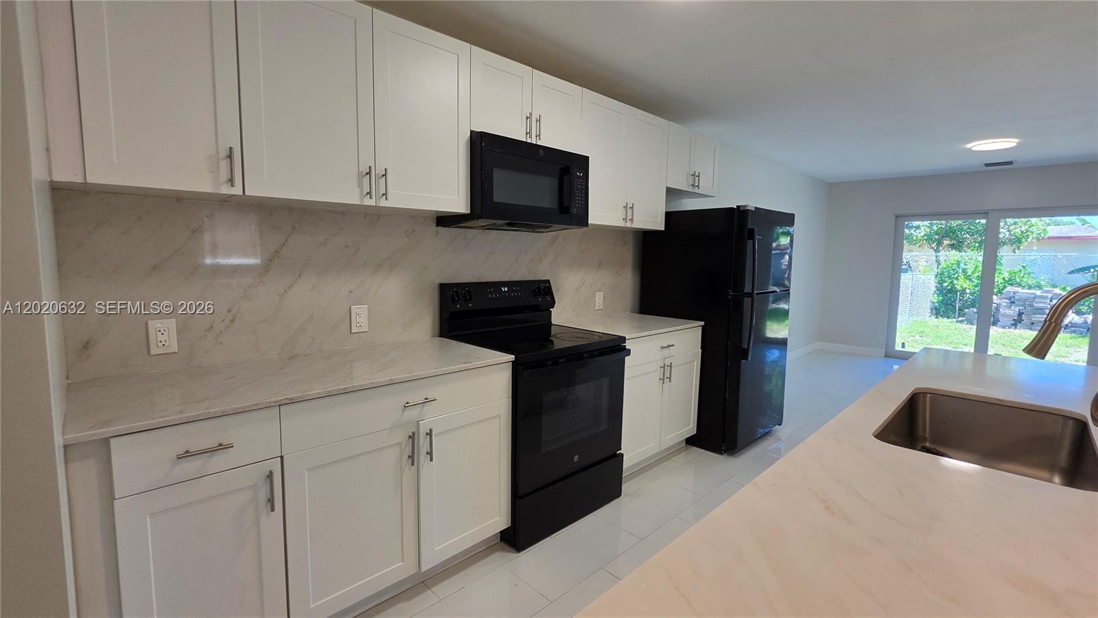 A kitchen features white cabinets, black appliances, and marble-look countertops — 1068 NW 112th St # 1068, Miami FL 33168, MIAMI, FL