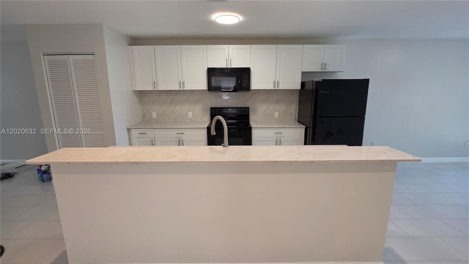 A kitchen features white cabinets, black appliances, and a marble-patterned countertop on the island — 1068 NW 112th St # 1068, Miami FL 33168, MIAMI, FL