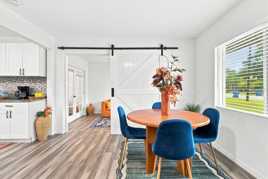 A dining area with a wooden table, blue chairs, and a sliding barn door — 6350 60TH AVENUE N, ST PETERSBURG, FL