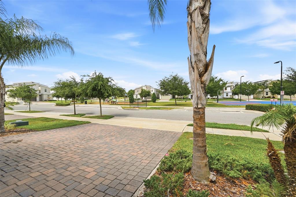 A paved driveway leads toward a residential street with a park and playground in the distance — 877 OCEAN COURSE AVENUE UNIT 877, DAVENPORT, FL