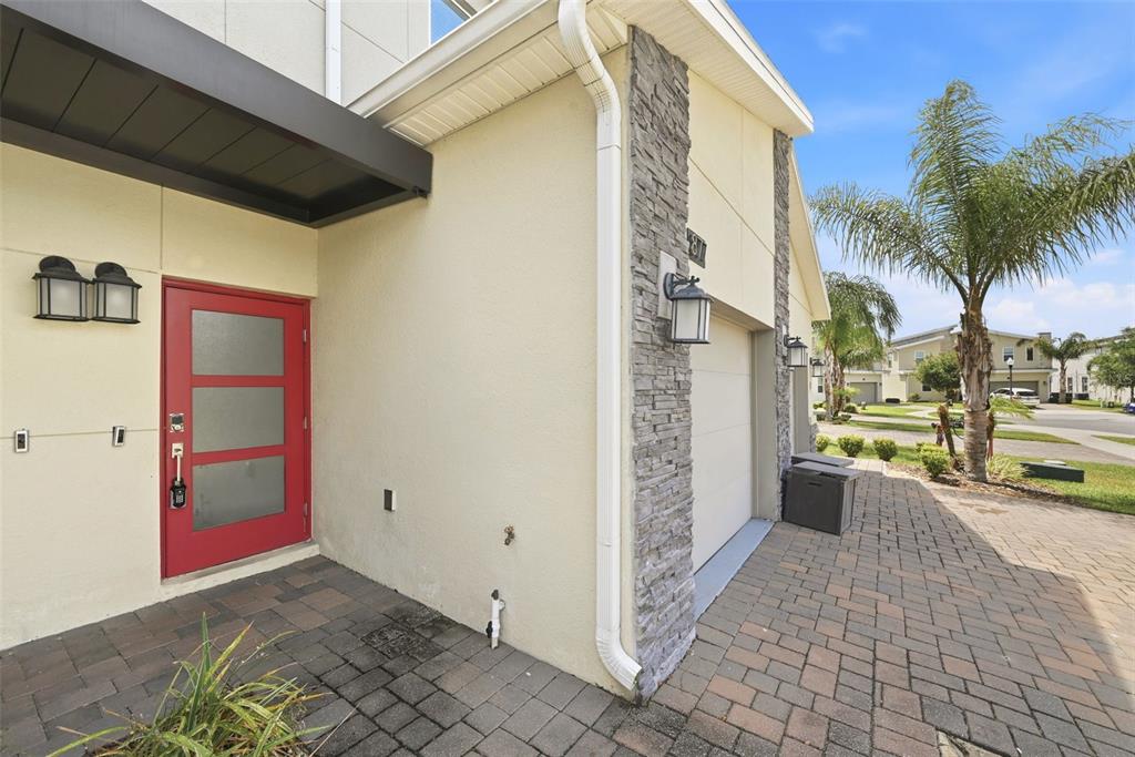 A red front door and a stone-accented garage entrance are visible on this home exterior — 877 OCEAN COURSE AVENUE UNIT 877, DAVENPORT, FL