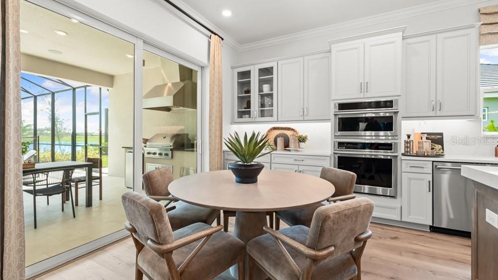A kitchen with white cabinets, a round dining table, and a view of a patio — 26112 ASPARANO AVENUE, ENGLEWOOD, FL