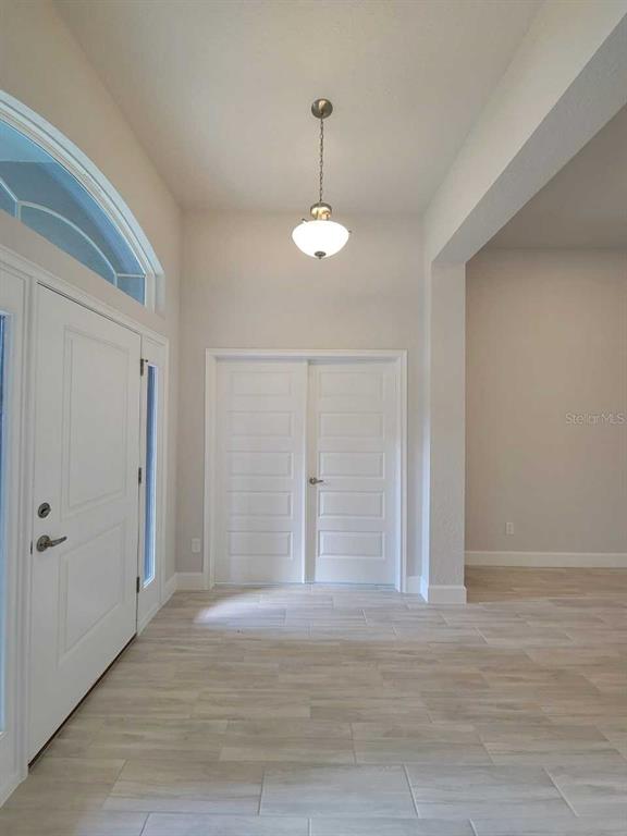 An entryway features light-colored tile flooring, a hanging pendant light, and white double doors — 4404 SW 110TH STREET, OCALA, FL