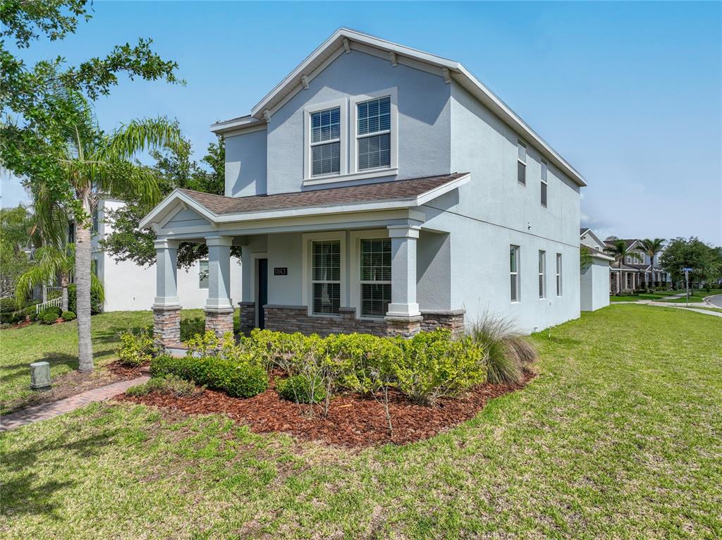 A two-story house with light blue stucco siding, a front porch, and stone accents — 11143 SYCAMORE WOODS DRIVE, ORLANDO, FL