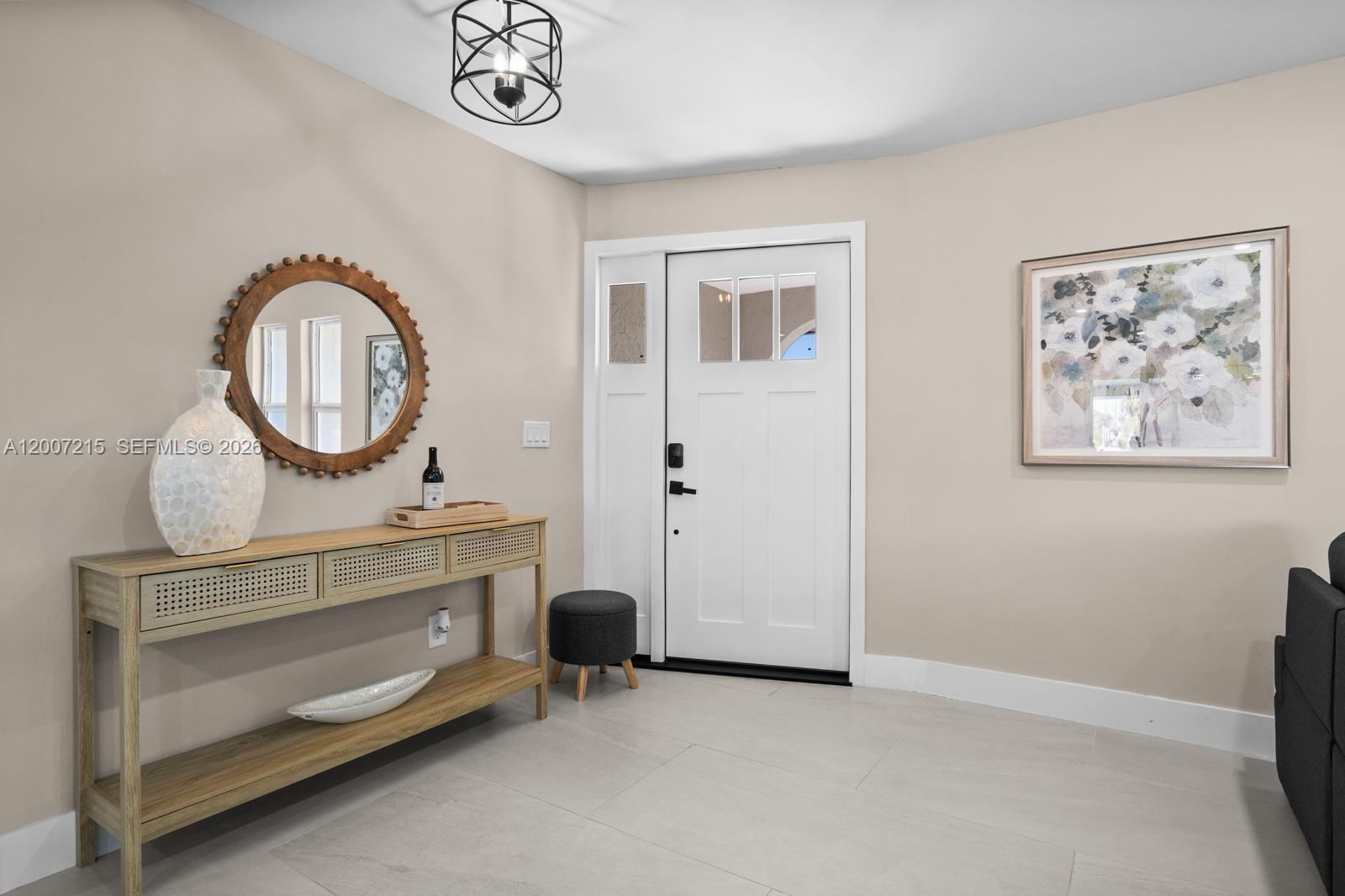 This entryway features a wooden console table, a round mirror, and a white front door — 117 SE 40 TER, Cape Coral FL 33904, CAPE CORAL, FL
