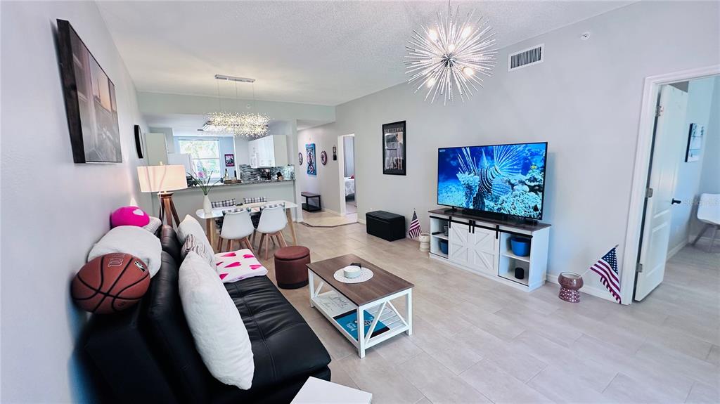 A living room with a black sofa, a television on a white stand, and dining area — 4640 TOWER HILL LANE UNIT 2315, SARASOTA, FL