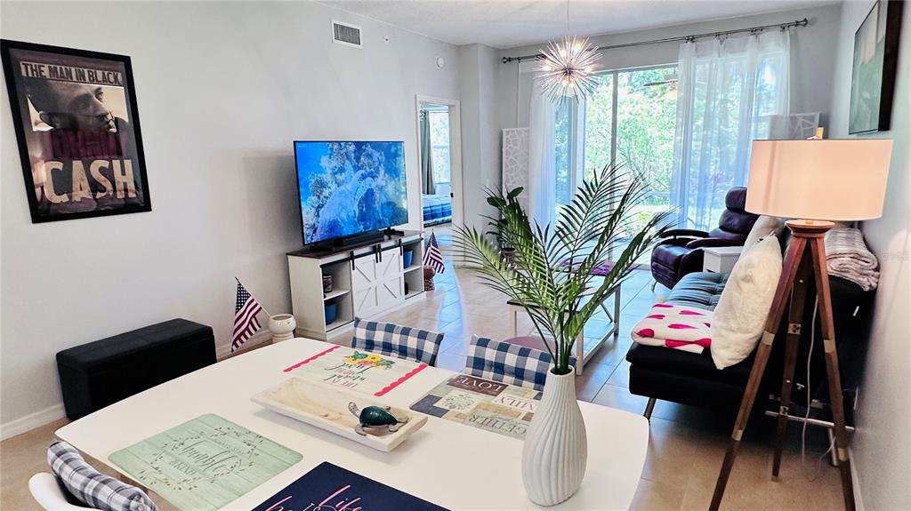 A dining area with a white table and chairs opens into a living room — 4640 TOWER HILL LANE UNIT 2315, SARASOTA, FL