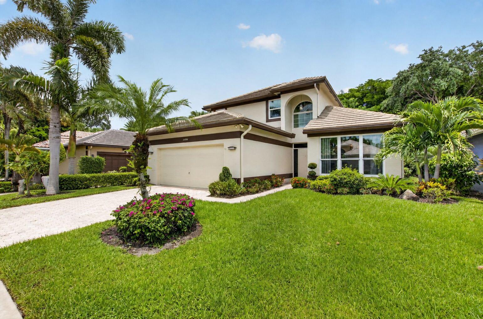 A two-story suburban house with a beige stucco exterior, a two-car garage, and palm trees — 13494 Carrick Green Court, Delray Beach FL 33446, DELRAY BEACH, FL
