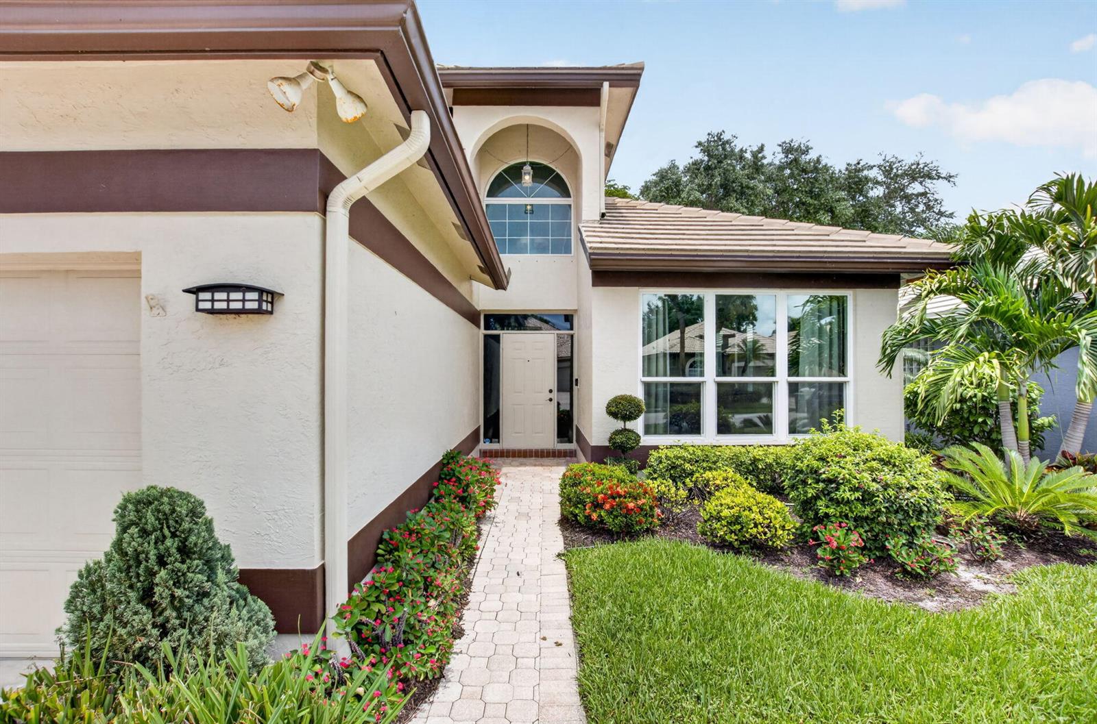 The exterior of a stucco house features a paved walkway leading to the front entrance — 13494 Carrick Green Court, Delray Beach FL 33446, DELRAY BEACH, FL