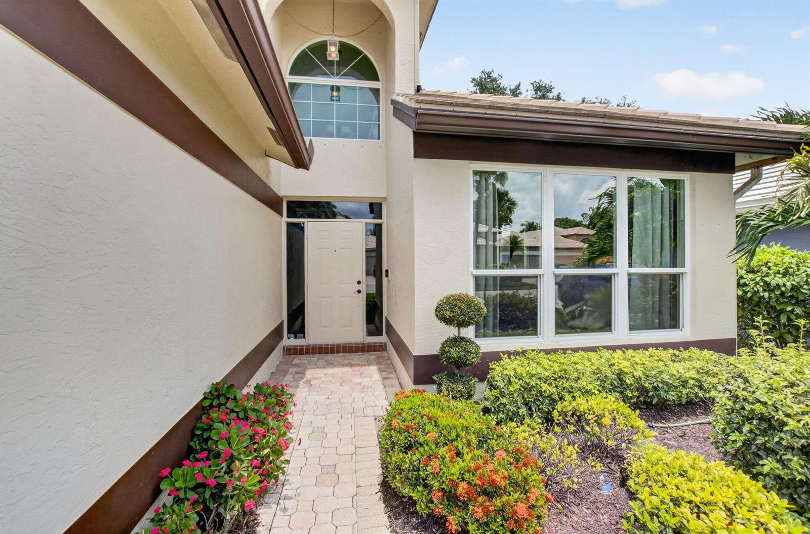 The exterior of a house features a paved walkway, a front door, and landscaped bushes — 13494 Carrick Green Court, Delray Beach FL 33446, DELRAY BEACH, FL
