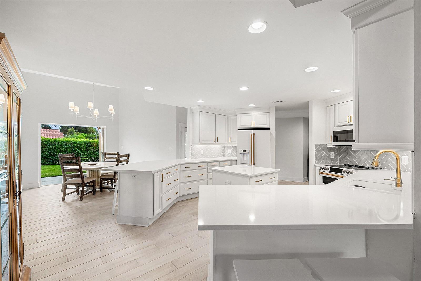 A bright, open-concept kitchen features white cabinetry, quartz countertops, and a breakfast bar — 23373 Water Circle, Boca Raton FL 33486, BOCA RATON, FL