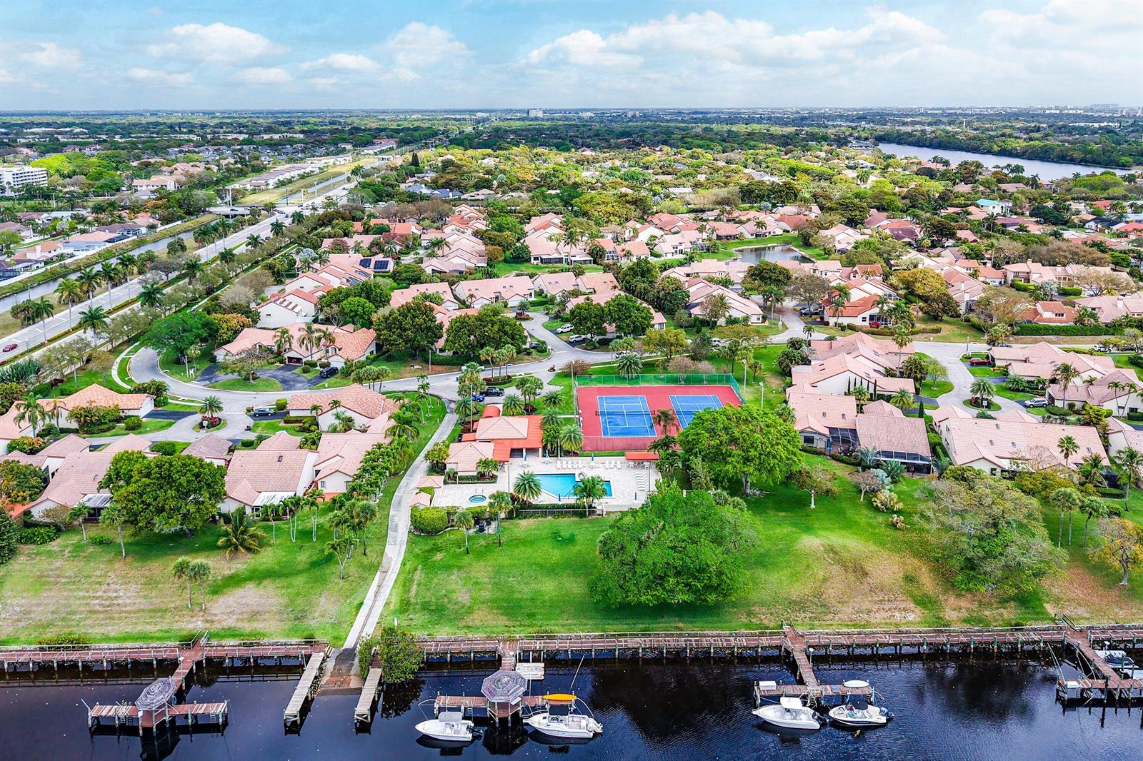 An aerial view shows two boats docked at a wooden pier in front of waterfront homes — 23373 Water Circle, Boca Raton FL 33486, BOCA RATON, FL