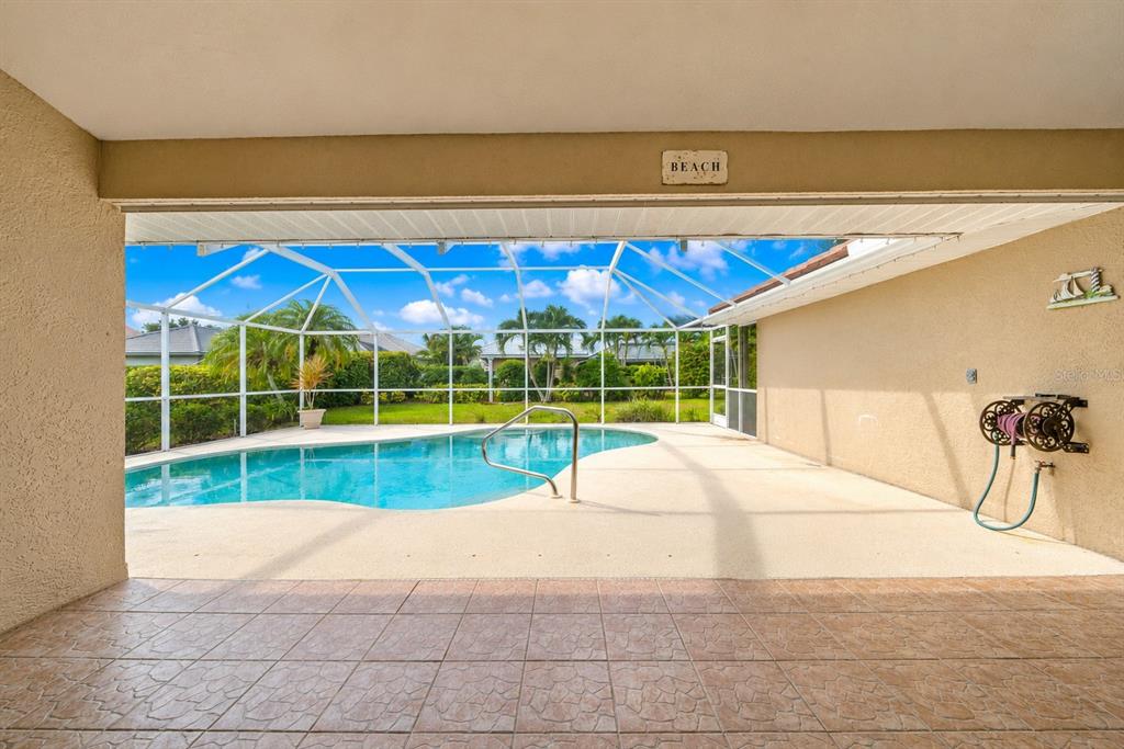 A covered patio with tile flooring overlooks a screened-in swimming pool and backyard — 555 PARK ESTATES SQUARE, VENICE, FL