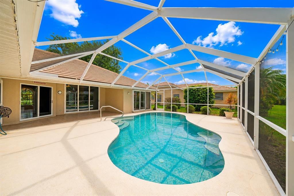 A screened-in patio features a swimming pool with a tan deck and white metal framing — 555 PARK ESTATES SQUARE, VENICE, FL