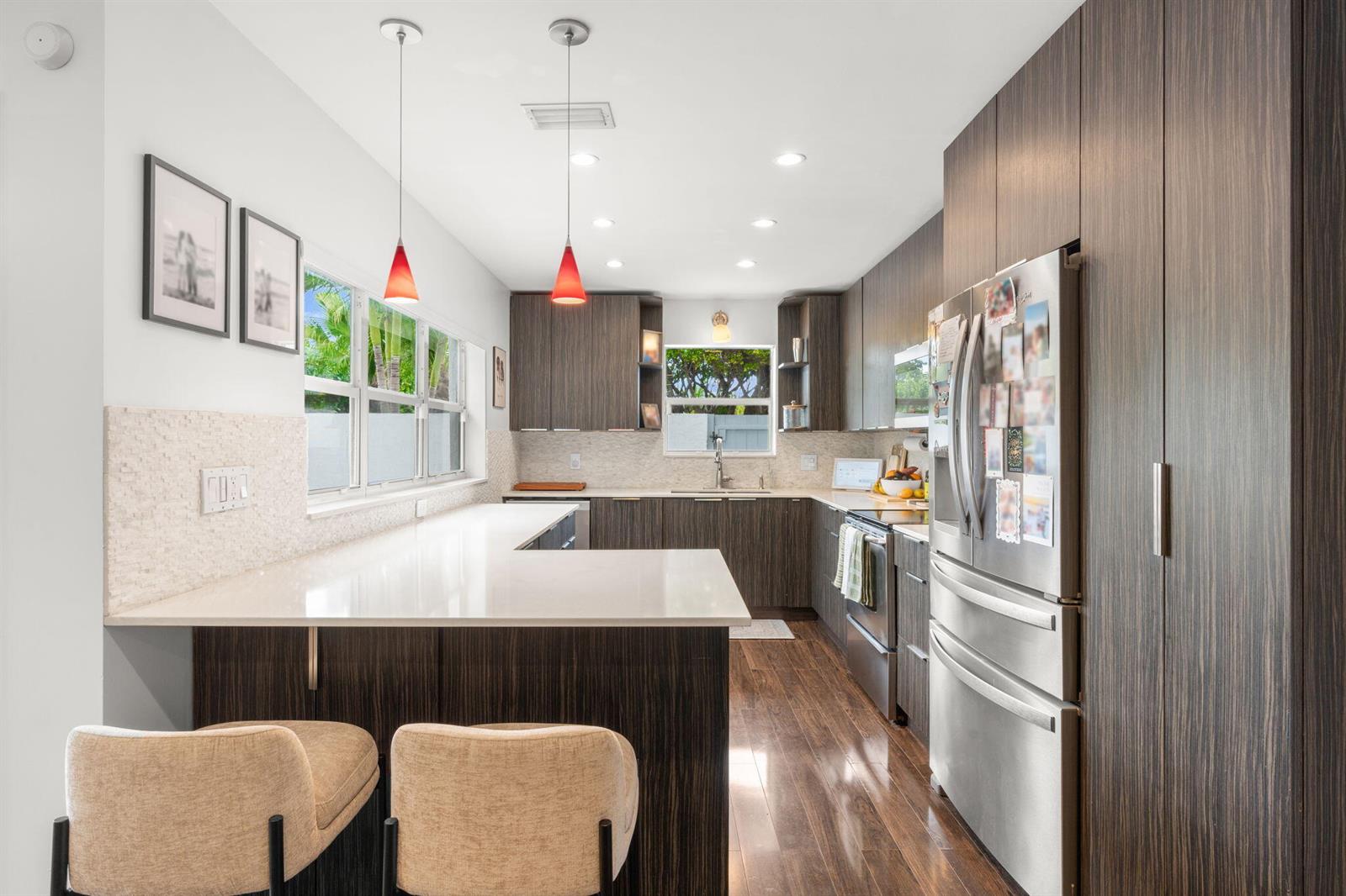 A modern kitchen features dark wood cabinetry, white countertops, stainless steel appliances, and two barstools — 2956 Florida Boulevard, Delray Beach FL 33483, DELRAY BEACH, FL