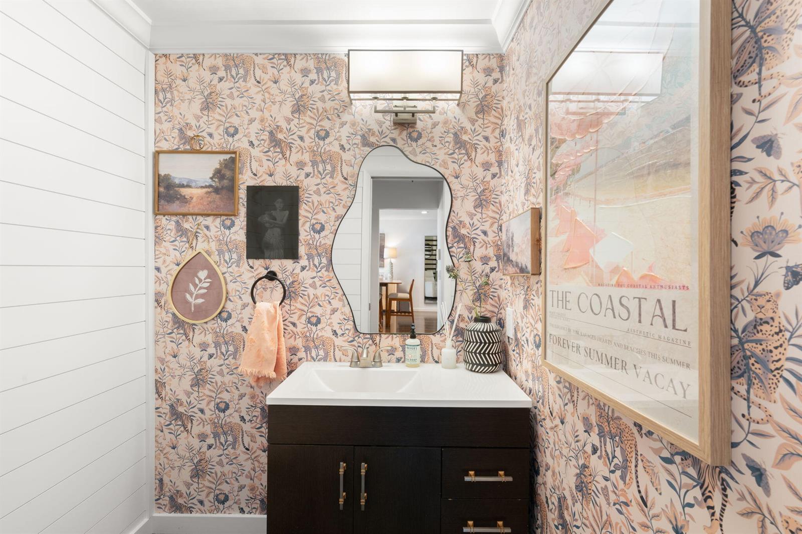 A powder room features patterned floral wallpaper, a dark vanity, and an asymmetrical wall mirror — 2956 Florida Boulevard, Delray Beach FL 33483, DELRAY BEACH, FL
