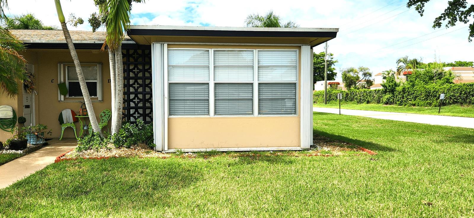 A tan exterior wall with a large three-pane window and a decorative privacy screen — 1042 North Drive # D, Delray Beach FL 33445, DELRAY BEACH, FL