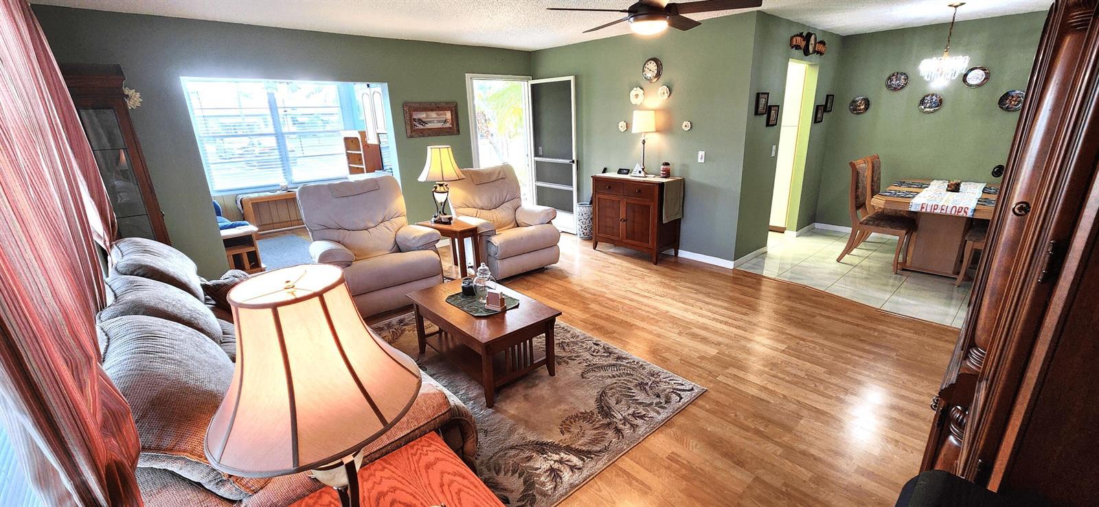 A living room with wood floors, green walls, and an adjacent dining area — 1042 North Drive # D, Delray Beach FL 33445, DELRAY BEACH, FL