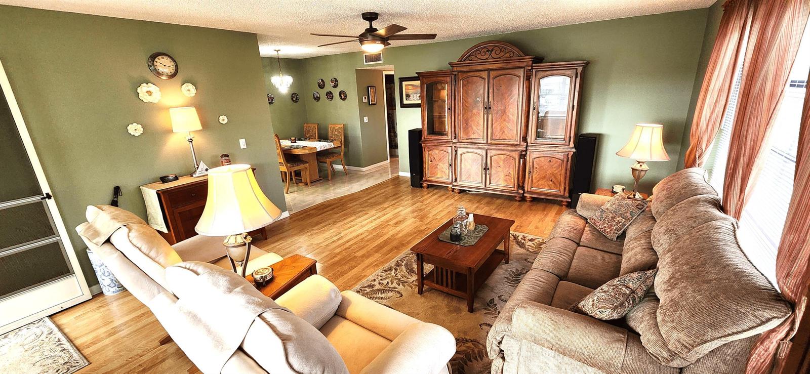A living room with hardwood floors, a large wooden entertainment center, and a dining area — 1042 North Drive # D, Delray Beach FL 33445, DELRAY BEACH, FL