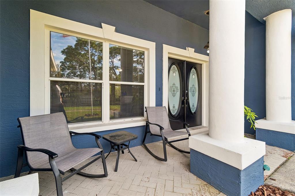 A covered front porch features two rocking chairs, a small table, and double entry doors — 12916 ITHACA AVENUE, HUDSON, FL