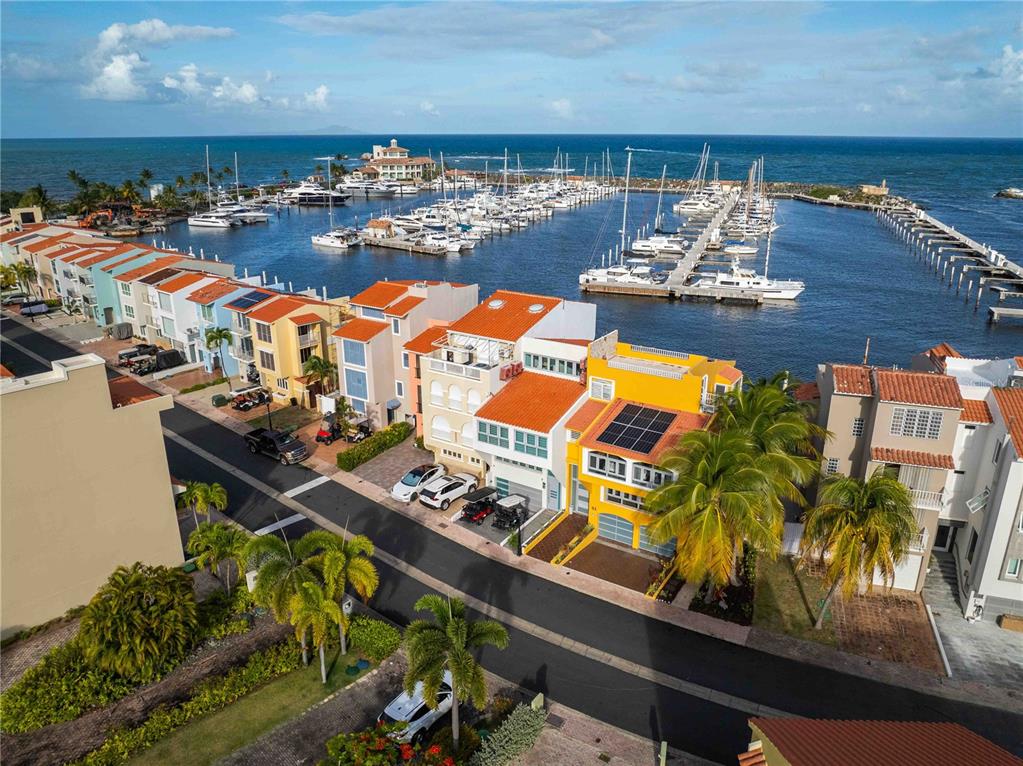 An aerial view shows colorful waterfront townhomes with a marina and the ocean beyond — 53 ISLA SAN MIGUEL, HUMACAO, PR