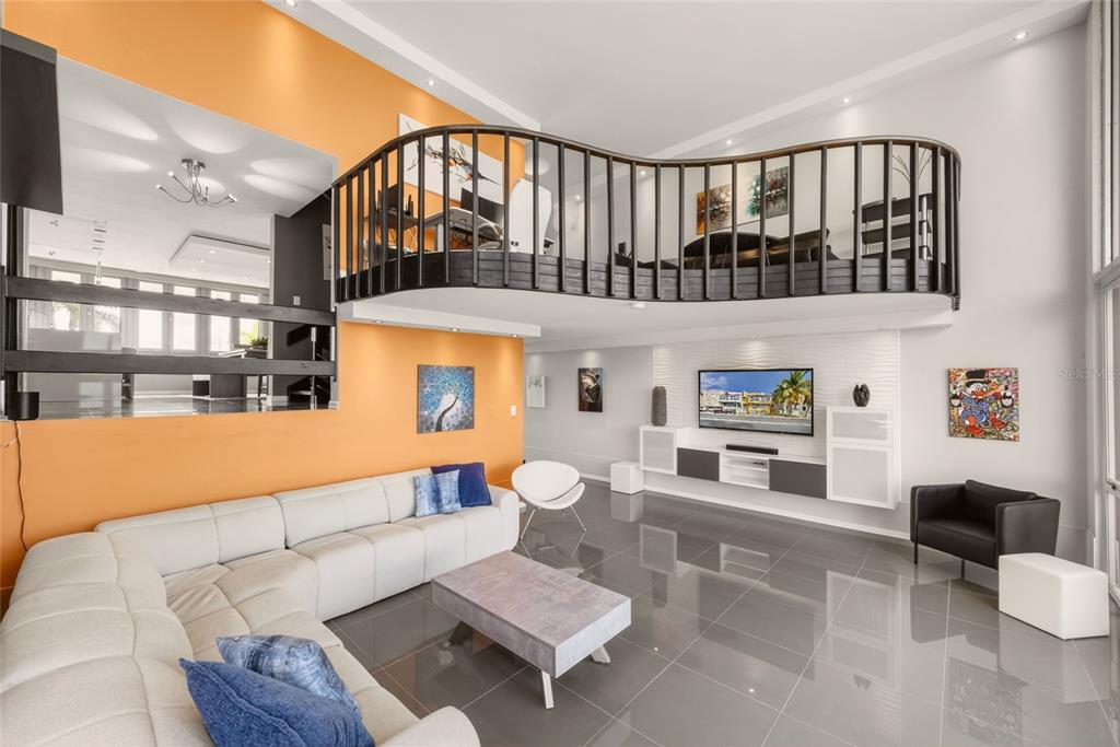 A modern living room features a white sectional sofa, orange wall, and a lofted balcony — 53 ISLA SAN MIGUEL, HUMACAO, PR