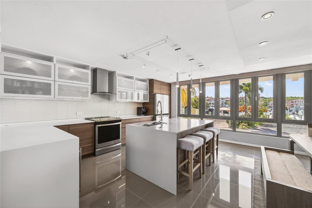 A modern kitchen features white countertops, wood cabinetry, a central island, and floor-to-ceiling windows — 53 ISLA SAN MIGUEL, HUMACAO, PR