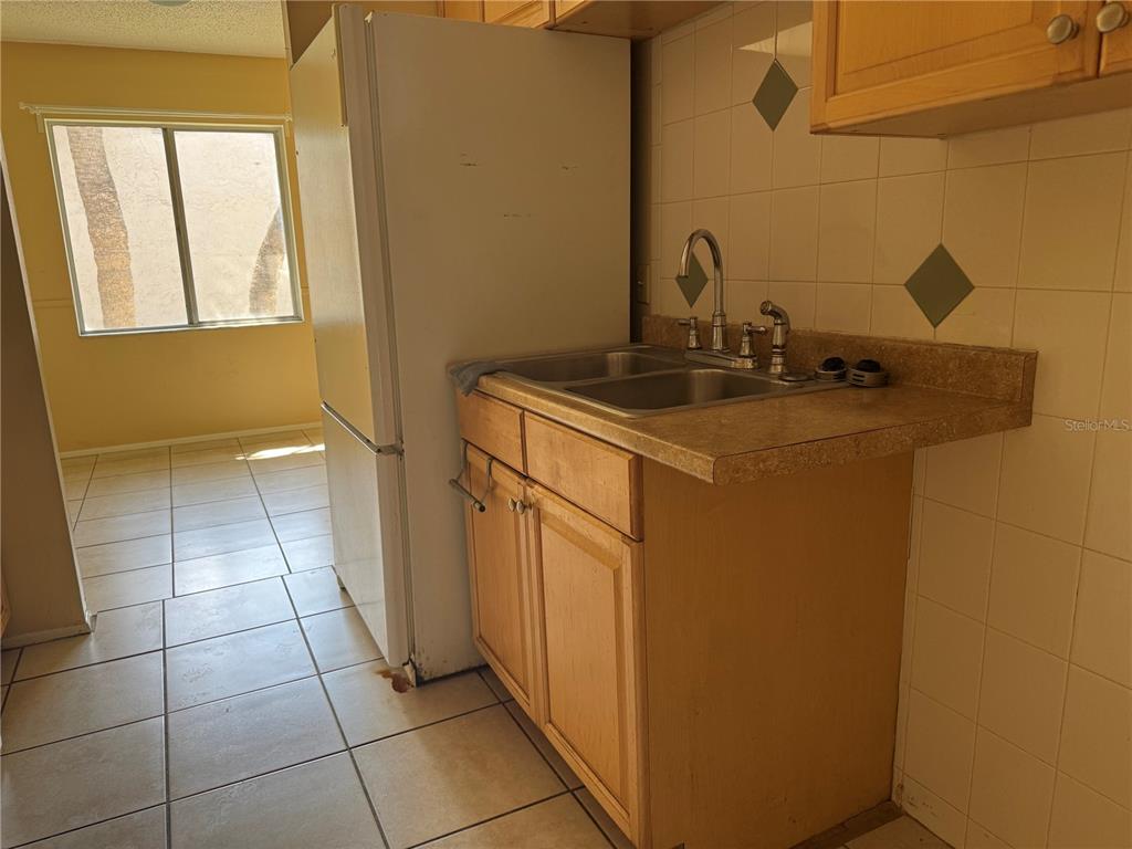 A kitchen features light wood cabinets, a double sink, and a white refrigerator — 7512 NEEDLE LEAF PLACE UNIT 52, TAMPA, FL