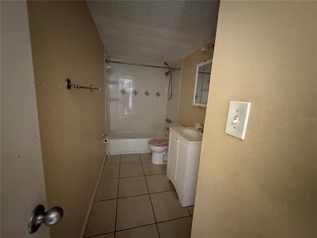 A bathroom features a white vanity, a toilet, and a shower-tub combination with tiled walls — 7512 NEEDLE LEAF PLACE UNIT 52, TAMPA, FL