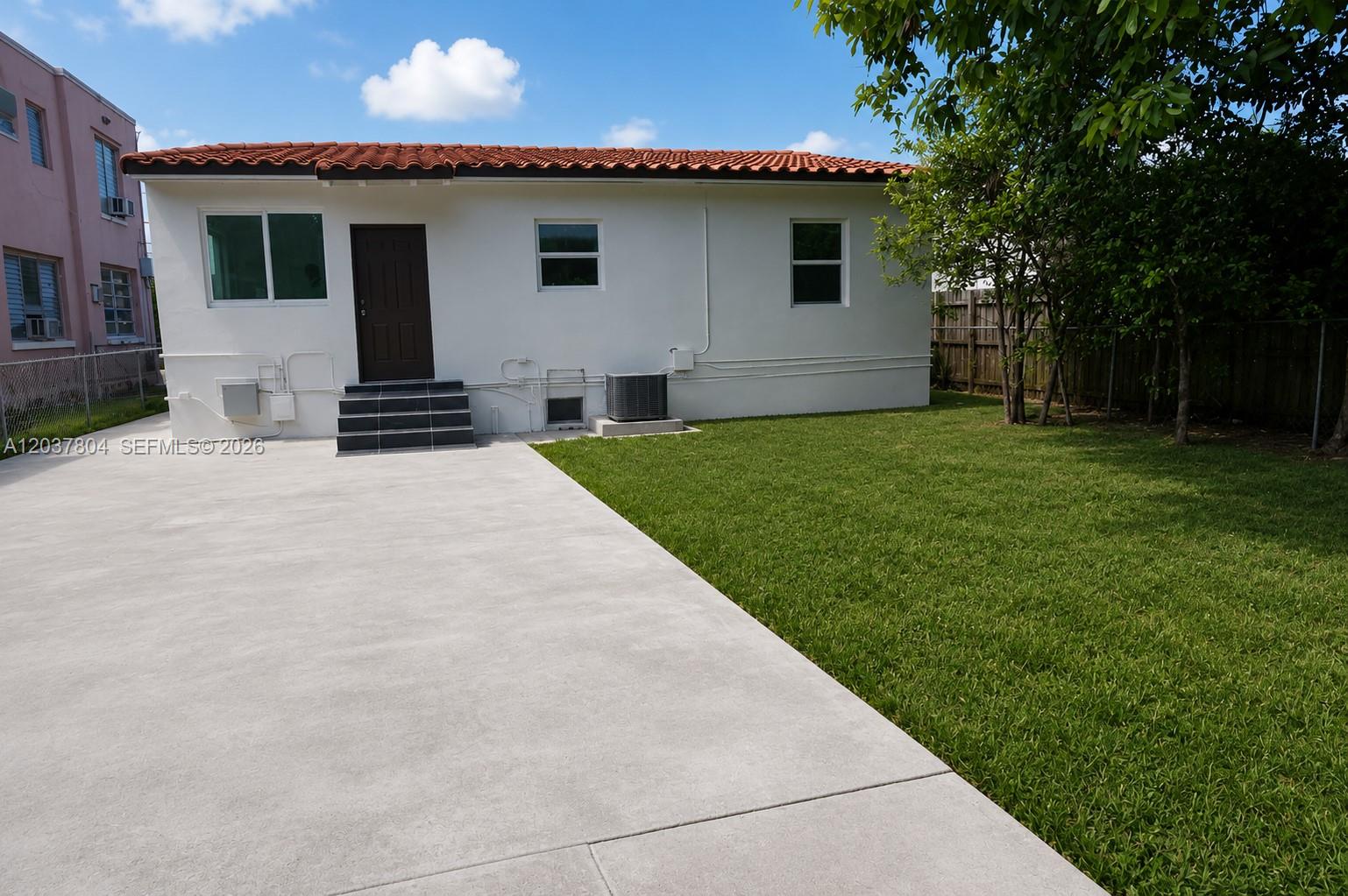 The exterior of a white house features a red tile roof and a concrete patio — 4240 SW 14th St, Miami FL 33134, MIAMI, FL