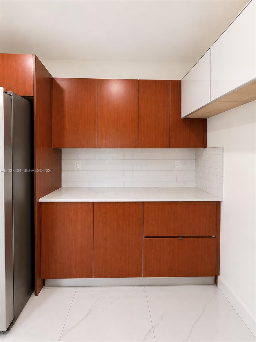 A kitchen area features wood-toned cabinets, white countertops, and a white subway tile backsplash — 4240 SW 14th St, Miami FL 33134, MIAMI, FL