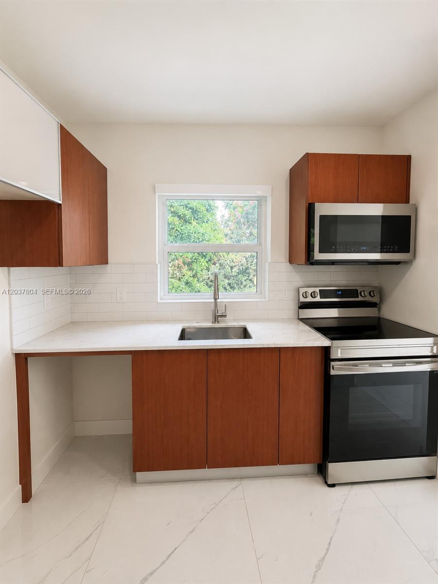 A kitchen features wood cabinets, stainless steel appliances, white subway tile, and marble-look flooring — 4240 SW 14th St, Miami FL 33134, MIAMI, FL