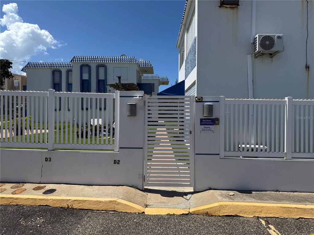 A white metal gate provides entry to a residential property with a white fence — COND. LAS CABANAS CARR 466 KM 8.9 UNIT D2, ISABELA, PR