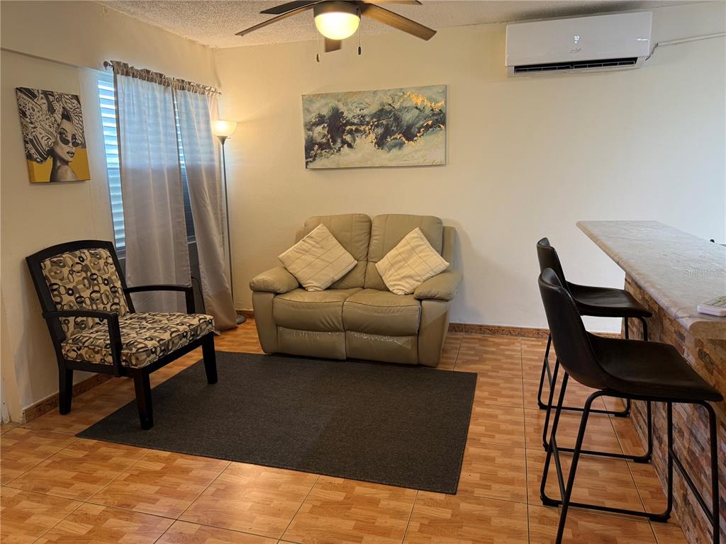 A living room features a loveseat, an armchair, a rug, and a breakfast bar — COND. LAS CABANAS CARR 466 KM 8.9 UNIT D2, ISABELA, PR