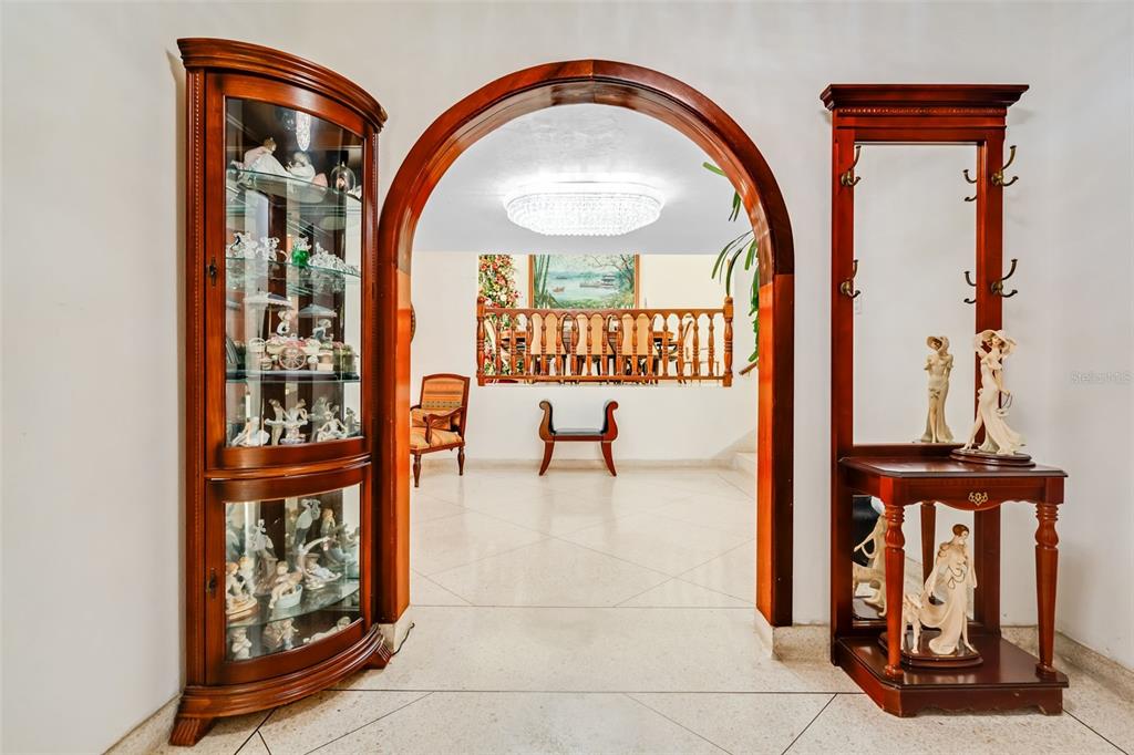 An arched doorway leads to a room with a chandelier, wooden railing, and tiled floors — B CONSTITUCION ST. EL RETIRO DEVELOPMENT LOT A-4, CAGUAS, PR