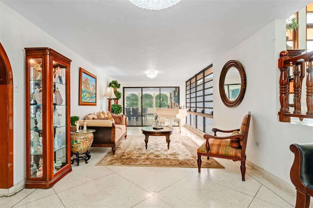 A living room features a display cabinet, a sofa, a piano, and tile flooring — B CONSTITUCION ST. EL RETIRO DEVELOPMENT LOT A-4, CAGUAS, PR