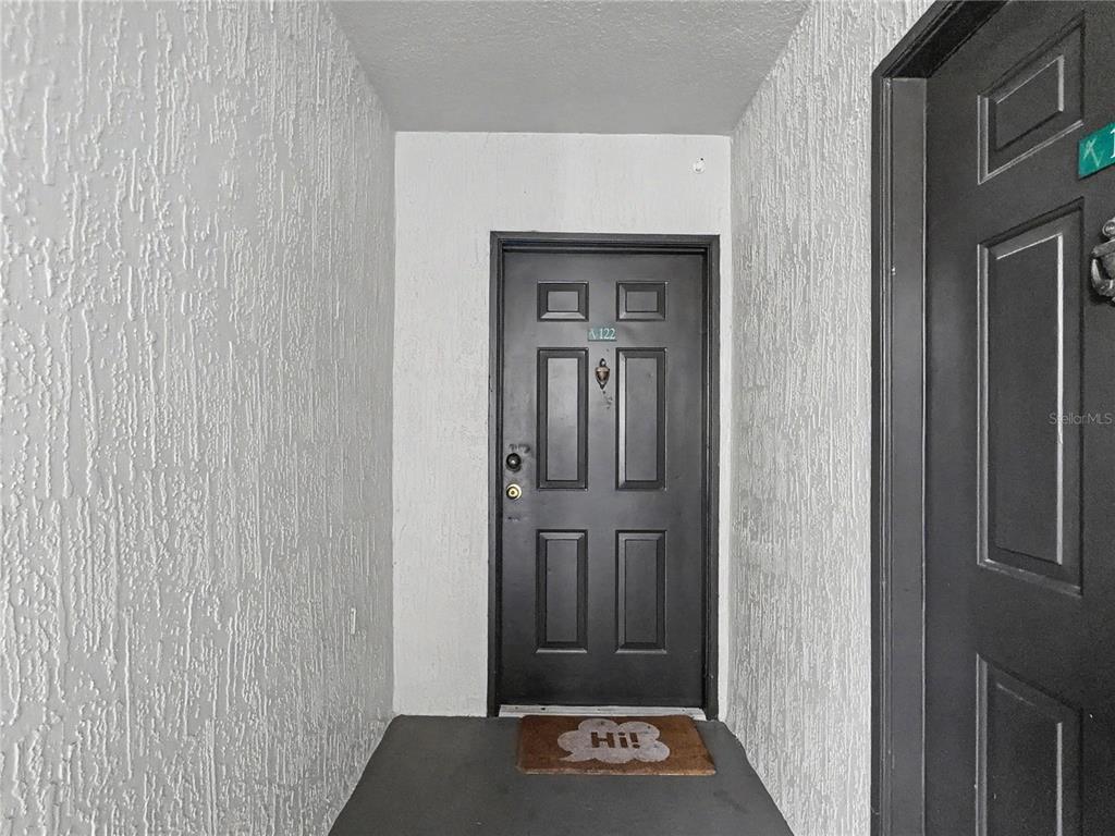 A dark front door with a door knocker and a welcome mat in an entryway — 14049 FAIRWAY ISLAND DRIVE UNIT 122, ORLANDO, FL
