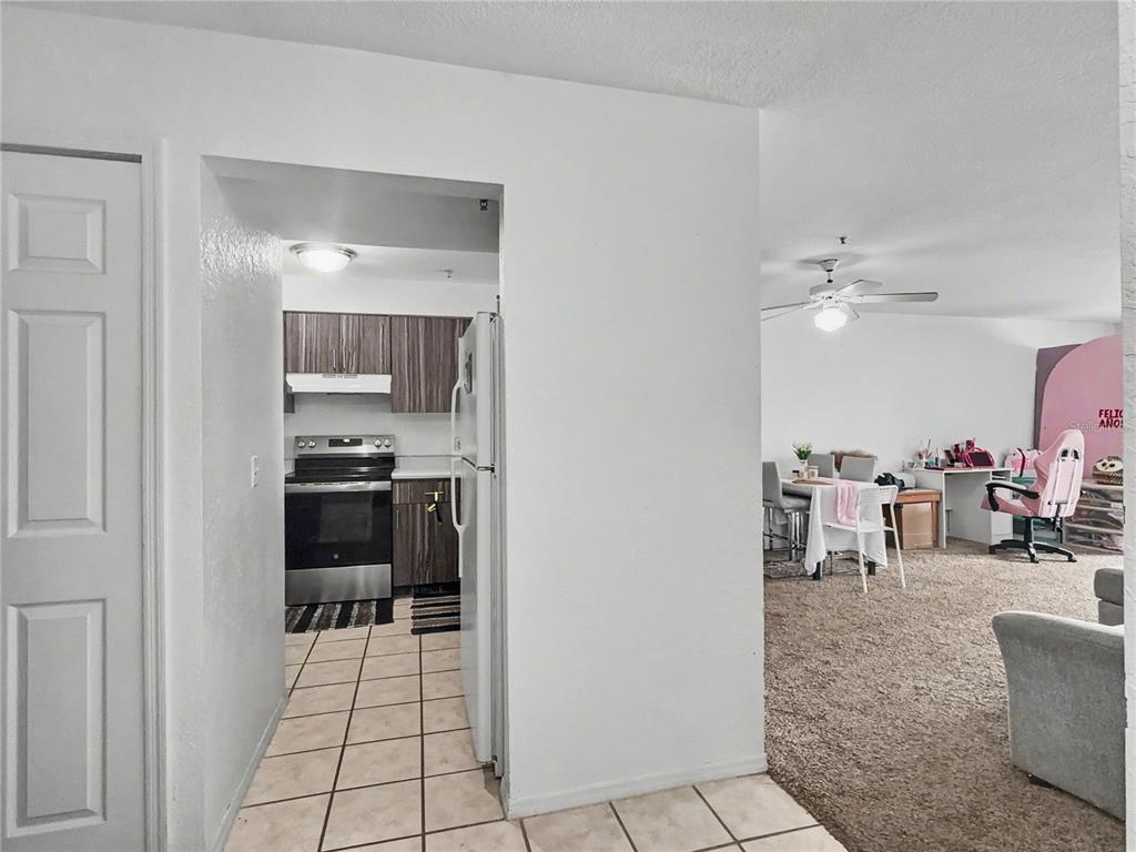 A view from a tiled kitchen entryway looking into a carpeted living and dining area — 14049 FAIRWAY ISLAND DRIVE UNIT 122, ORLANDO, FL