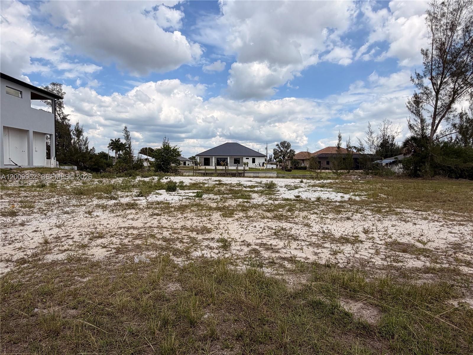 A vacant, sandy residential lot sits in front of a canal and neighboring houses — 2329 NW 36TH PL, Cape Coral FL 33993, CAPE CORAL, FL