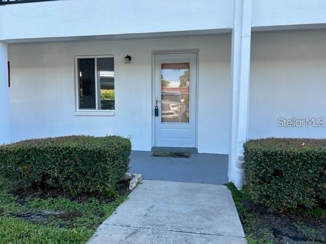 A white exterior wall features a single window and a front door with a storm door — 2060 MARILYN STREET UNIT 124, CLEARWATER, FL