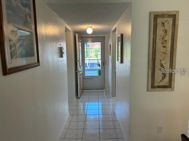 A tiled hallway leads to an open front door showing a view of the outdoors — 2060 MARILYN STREET UNIT 124, CLEARWATER, FL