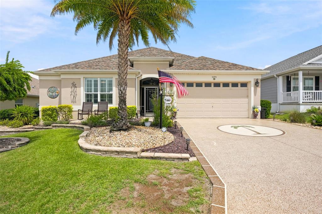 A single-story house with a palm tree, a beige garage, and a paved driveway — 3095 KRAMER COURT, THE VILLAGES, FL