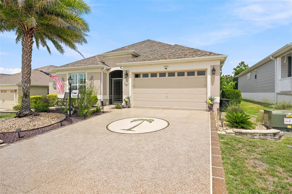 A single-story house with a beige stucco exterior, a two-car garage, and a palm tree — 3095 KRAMER COURT, THE VILLAGES, FL