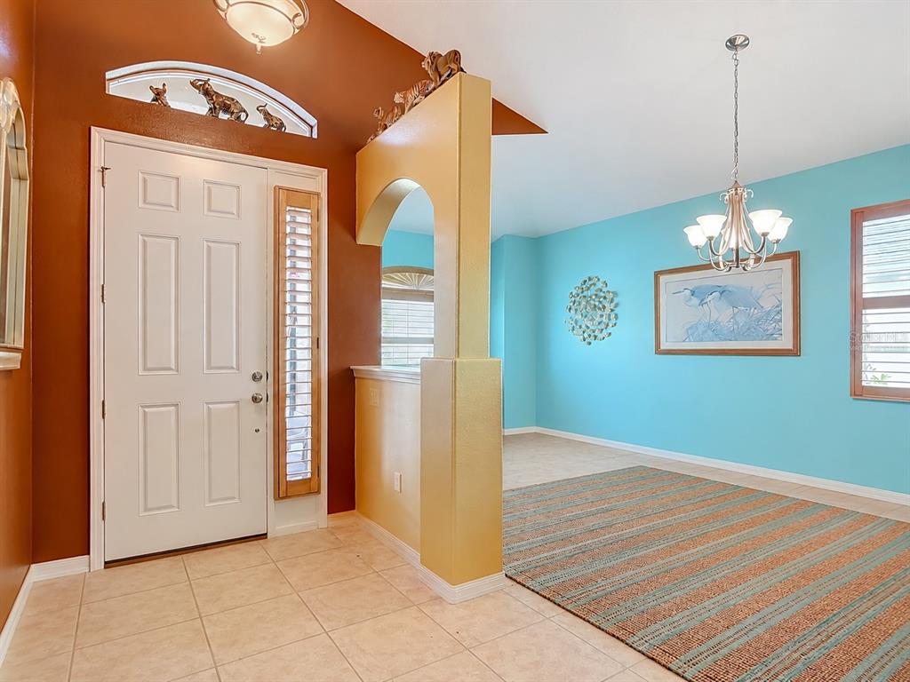 An entryway with a tiled floor, a yellow arched partition, and a turquoise dining room — 111 S HUMMINGBIRD PLACE, PALM COAST, FL