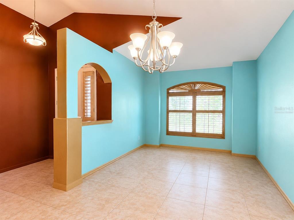 A dining room features light blue walls, a brown accent wall, tile flooring, and a chandelier — 111 S HUMMINGBIRD PLACE, PALM COAST, FL