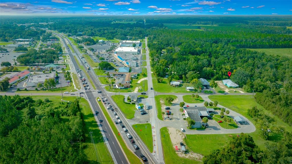 An aerial view shows a commercial property with a red location pin near a highway — 1415 NW 23RD AVENUE, CHIEFLAND, FL