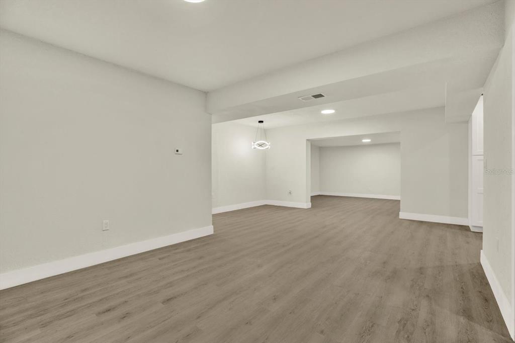An open-concept room features light gray walls, white trim, and wood-look flooring — 3606 AUTUMN PALM DRIVE, ZEPHYRHILLS, FL