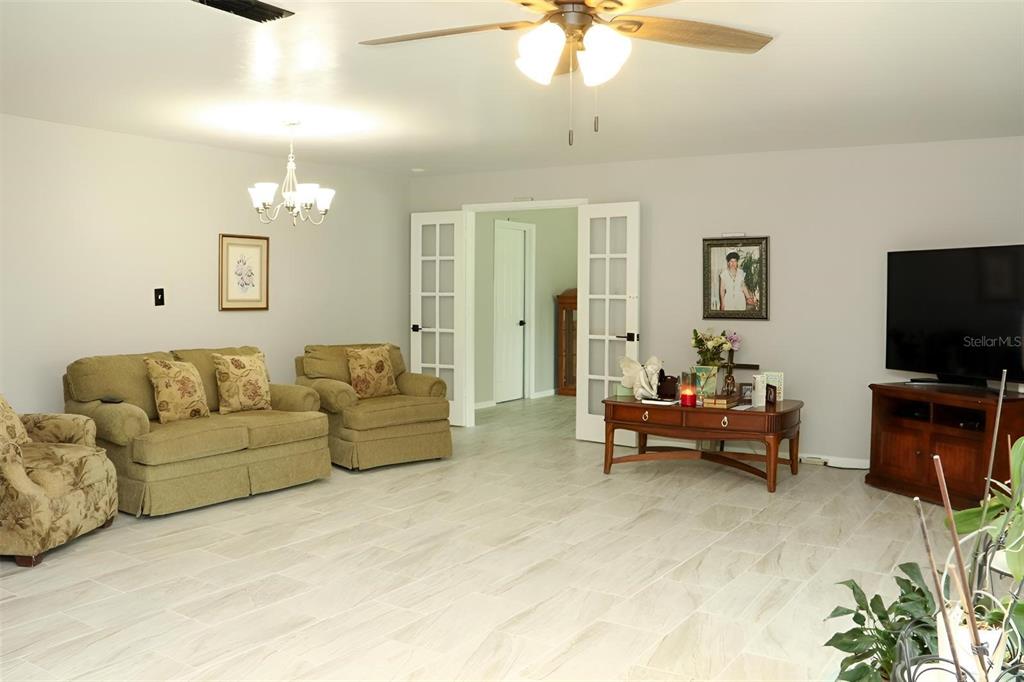 A living room features light tile flooring, a ceiling fan, and French doors — 8424 NW 2 PLACE, GAINESVILLE, FL