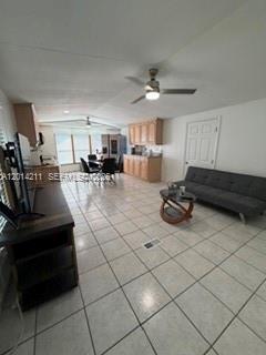 An open-concept living room and kitchen area features light tile flooring and wooden cabinetry — 114 Lone Pine Drive, Hallandale Beach FL 33009, HALLANDALE BEACH, FL